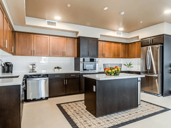 A kitchen with a black island and stainless steel appliances.